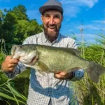 A fisherman holding a bass at night with a colorful lure